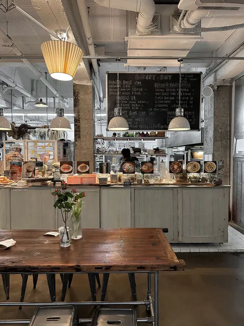 Quầy bánh mở bên trong Bake No Title với bảng đen viết tay thực đơn 'BAKERY & BUT', nhân viên đang bày bánh lên quầy