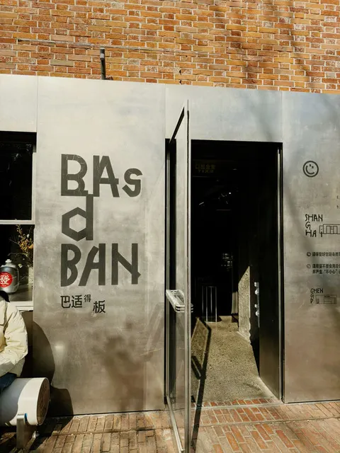Mặt tiền BAsdBAN với chữ '巴适得板' sơn trên tường thép không gỉ, tường gạch đỏ phía trên tương phản phong cách công nghiệp