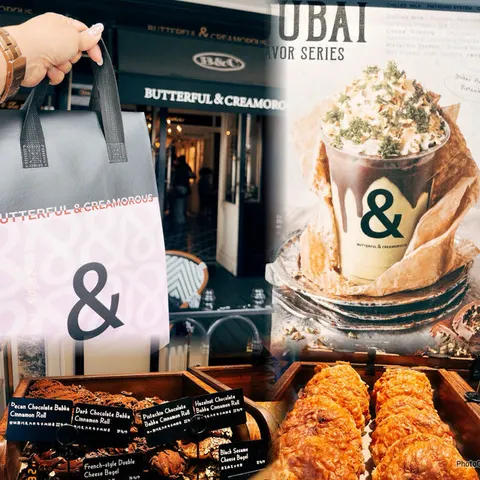 Mặt tiền BUTTERFUL & CREAMOROUS với biển hiệu đen, khách cầm túi tote xám-hồng in logo '&' ngay trước cửa