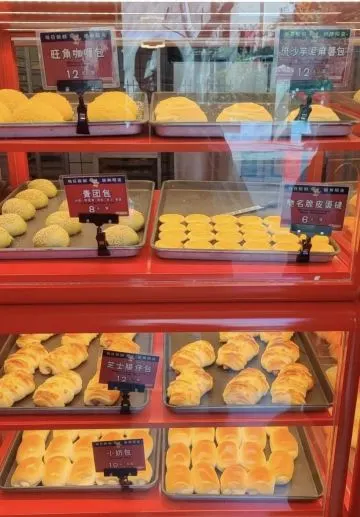 Tủ bánh khung đỏ ba tầng của 福福饼店 chi nhánh Réel Mall, khay bánh bao tròn vàng và bánh ngàn lớp, mỗi khay có bảng tên và giá