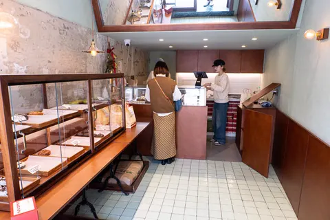 Không gian nhỏ bên trong nunu DONUT với tủ kính bày donut và quầy thanh toán, tường gạch mộc