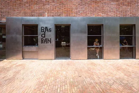 Mặt tiền BAsdBAN ở 愚园路546号: tường gạch đỏ phía trên, mảng thép không gỉ chạy dài với ba ô cửa kính và chữ BAsdBAN màu đen