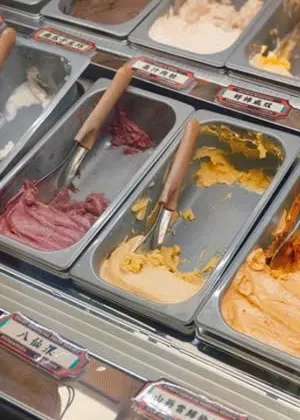 Tủ kem 忠曜堂 với các khay gelato nhiều màu, mỗi khay có thẻ tên vị