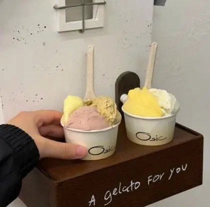 Hai cốc gelato Osic trên giá gỗ khắc chữ “A gelato for you”, gắn trên tường trắng