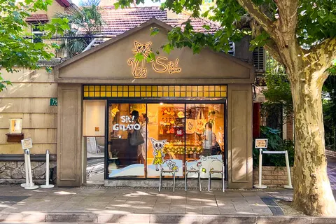 Mặt tiền Sit! Gelato trên đường Nam Xương, cổng vòm kiểu cổ điển với logo mèo phát sáng và bàn ghế trắng ngoài hiên