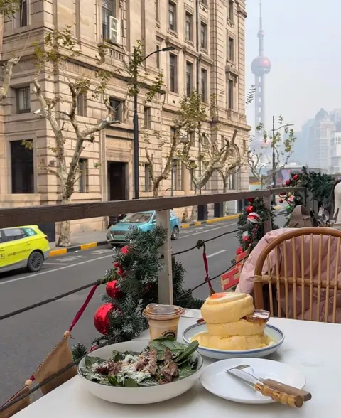 Bàn ngoài ban công với soufflé, salad bò và ly cà phê đá, nhìn ra phố và tháp Minh Châu — Dugout (ảnh An gửi)