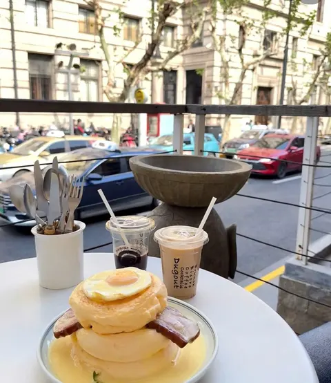 Soufflé kèm trứng ốp và thịt xông khói, hai ly cà phê đá, một ly in chữ Dugout, bàn ngoài hiên — Dugout (ảnh An gửi)