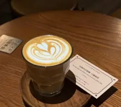 Latte ly thủy tinh trên đĩa gỗ cạnh thẻ mô tả hạt (ảnh An gửi)