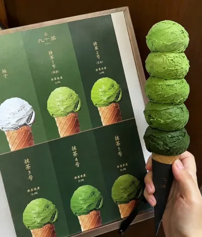 Cây kem ốc quế 5 viên matcha từ nhạt đến đậm, cầm cạnh bảng vị matcha đánh số của 九十葉 (ảnh An gửi, 08/10)