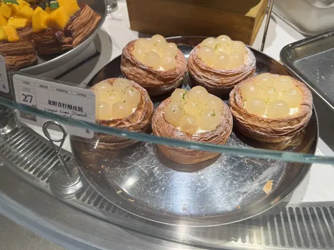 Khay bánh 龙眼青柠酥皮挞 (Longan Lime Danish) trong tủ kính bebaked, thẻ giá 27 元/cái