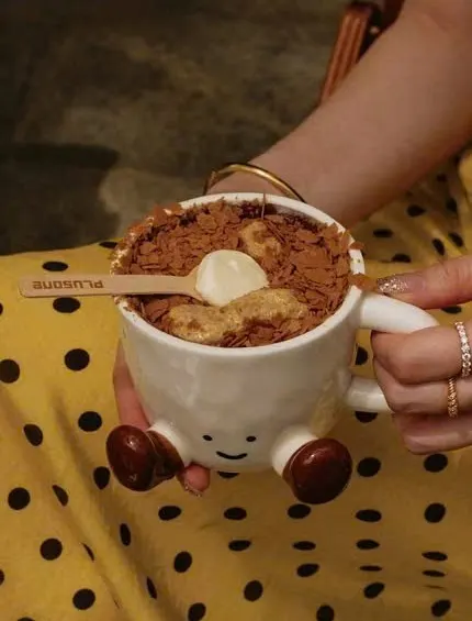 Tay cầm cốc tiramisu Plusone có hình mặt cười và chân gỗ, phủ bột cacao
