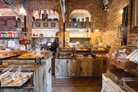 Quầy bagel bên trong New York Bagelous Museum với tường gạch trần, khay bánh bày đầy phía trước và kệ gỗ phía sau