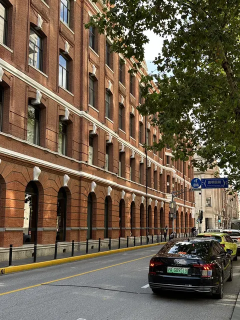 Dãy nhà gạch đỏ kiểu Anh trên đường Viên Minh Viên (圆明园路) trong khu Rockbund, với biển chỉ đường xanh ghi rõ tên phố, xe cộ qua lại
