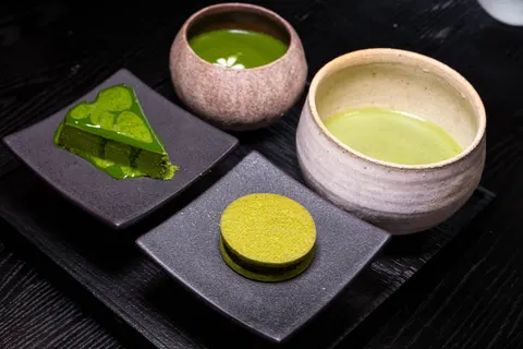 Khay tráng miệng matcha của White Foods trên khay đá tối màu, có lát bánh matcha và các món ngọt matcha khác