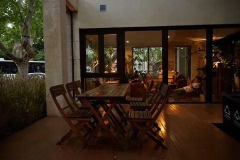 Khu bàn ngoài trời của 一尺花园 香樟花园店 buổi tối, bàn gỗ trước phòng kính sáng đèn