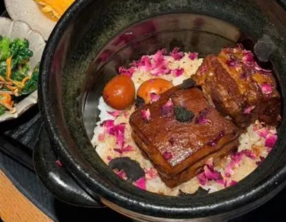 Niêu thịt kho hoa hồng (玫瑰红烧肉土锅饭) của White Foods: hai miếng thịt kho bóng trên cơm rắc cánh hoa hồng, bên cạnh trứng cuộn (ảnh An gửi)