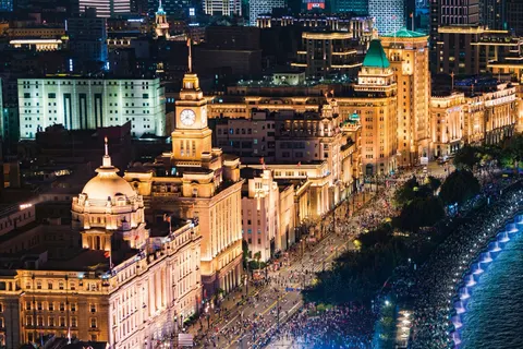 Dãy toà nhà cổ ở Bến Thượng Hải (The Bund) lên đèn vàng về đêm, nhìn từ trên cao, đường ven sông Hoàng Phố đông người (ảnh: Meet in Shanghai, trang du lịch chính thức của 上海市文化和旅游局)