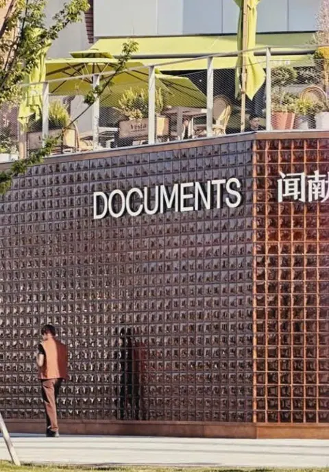 Mặt tiền 闻献 DOCUMENTS: tường ô kim loại sẫm màu với biển chữ trắng DOCUMENTS (ảnh An gửi)