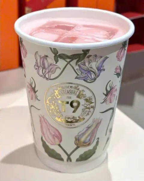 Ly trà đá màu hồng của T9 trong cốc giấy vẽ hoa tulip, huy hiệu T9 màu vàng (ảnh An gửi)