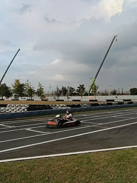 Một người đội mũ bảo hiểm lái xe kart cam-đen trên đường đua ngoài trời trong khuôn viên trường đua