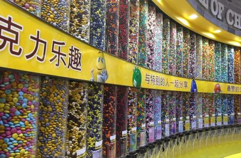 Bên trong M&M's World Shanghai, bức tường ống đựng kẹo M&M nhiều màu sắc với biển hiệu tiếng Trung