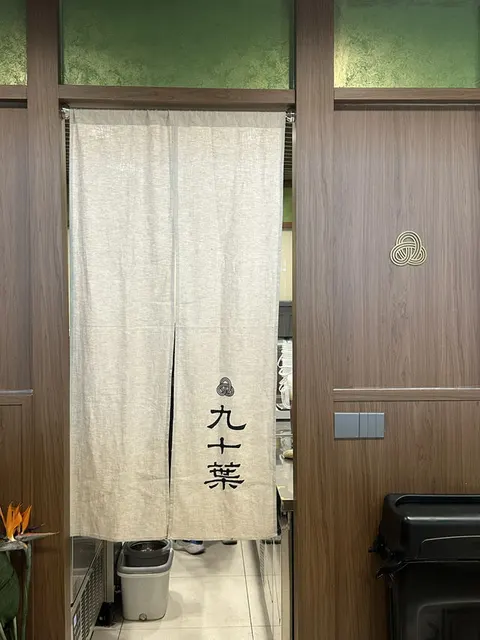 Tấm rèm vải noren in chữ 九十葉 treo trước lối vào khu pha chế, trang trí kiểu Nhật ấm cúng