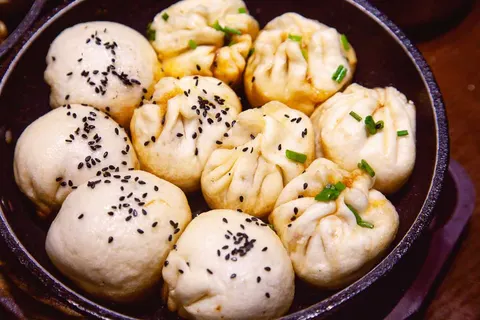 Chảo gang sinh tiền 大壶春 vừa chiên xong, vỏ bột trắng rắc mè đen và hành lá