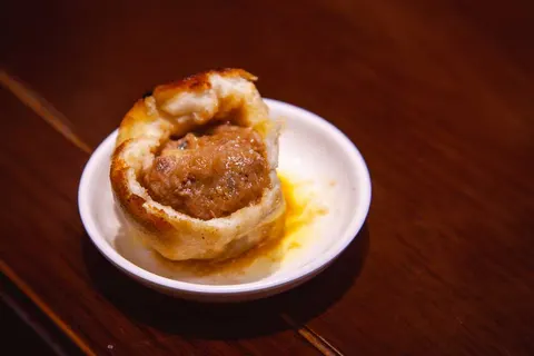 Bánh 烧饼 nhân thịt viên của 大壶春 trên đĩa sứ trắng