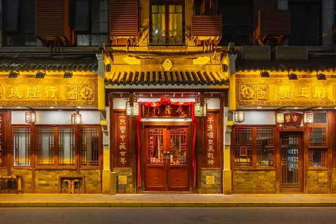 Mặt tiền 成隆行 ở 九江路 về đêm: mái ngói, cửa gỗ chạm, bảng hiệu vàng và đèn lồng hai bên