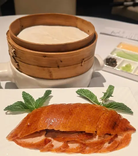 Đĩa vịt quay lạng mỏng da vàng cam, phía sau là xửng tre đựng bánh cuốn vịt và khay gia vị (ảnh An gửi)