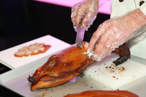 Cận cảnh da vịt quay giòn đang được lọc bằng dao
