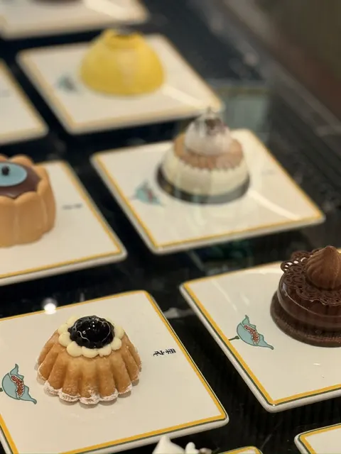 Khay bánh ngọt nhỏ bày trên đĩa sứ viền vàng có logo quả sung của Prada