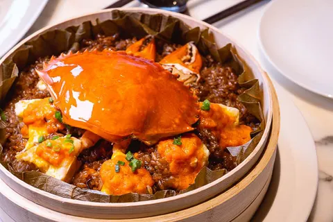 Món 厦门红蟳蒸米糕: nguyên con cua hấp đặt trên xôi nếp trong xửng tre