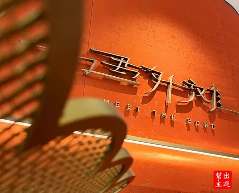 Bảng hiệu đồng '遇外滩 MEET THE BUND' ở lối vào nhà hàng, trên tường màu cam