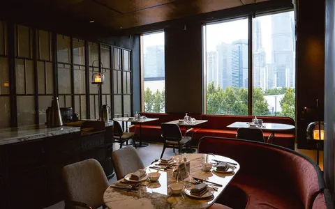 Phòng ăn Meet The Bund với bàn đá cẩm thạch và cửa kính nhìn ra đường chân trời Phố Đông