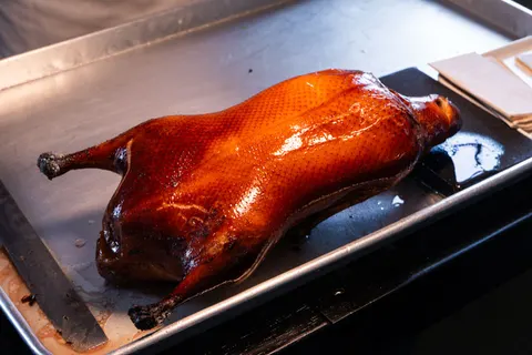 Vịt quay củi táo nguyên con da đỏ bóng của 晟永兴 trên khay kim loại trước khi lạng