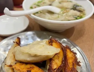 Bát hoành thánh nước có hành lá và thìa sứ phía sau, đĩa 煎饺 đáy chiên giòn phía trước; ảnh không cho biết chi nhánh (ảnh An gửi, 08/10)