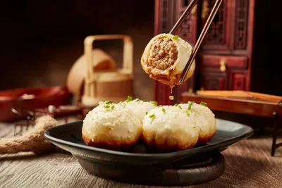 Bốn chiếc sinh tiền vàng ươm rắc vừng và hành lá, một chiếc bị cắn dở lộ nhân thịt và nước súp bên trong