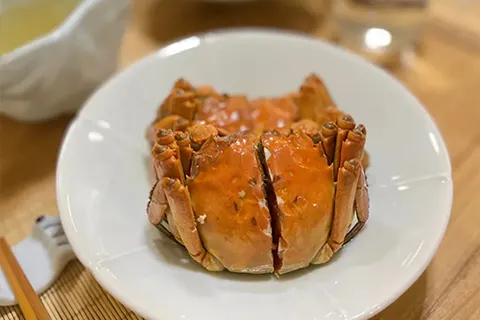 Một con cua lông hấp nguyên con bày trên đĩa trắng tại 蟹家大院