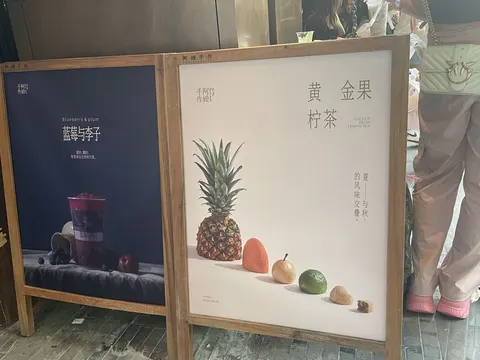 Hai bảng menu chữ A khung gỗ trước quán 阿嬷手作 新天地: bảng xanh đậm món 蓝莓与李子 và bảng màu kem món 黄金果柠茶