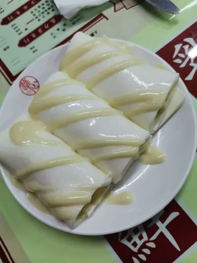 Một đĩa bánh cuốn ngọt kiểu Hồng Kông (肠粉 tráng miệng) phủ sốt sữa (ảnh khách đăng trên Trip.com, trang tiệm 南京西路)