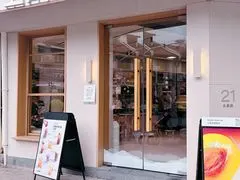 Mặt tiền kính của quán với số nhà '21' hiện rõ trên tường, ghế gỗ và kệ bày đồ uống phía trong