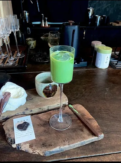 Ly matcha chân cao trên khay gỗ mộc ở Te Tea, cạnh chén gốm và tấm thẻ giới thiệu món (ảnh An gửi, 08/10)